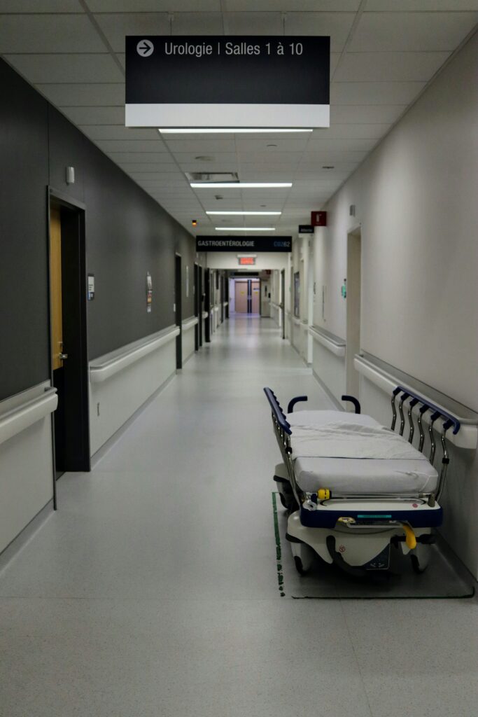A hospital hallway with an empty bed in it.