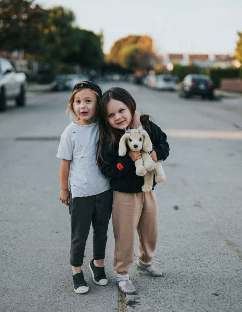 Two young girls hug on the street.