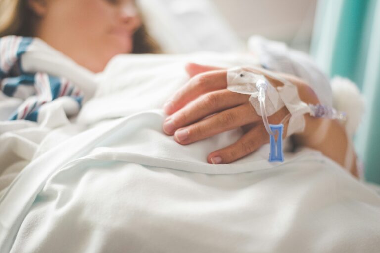 A patient lies in a hospital bed with an IV.