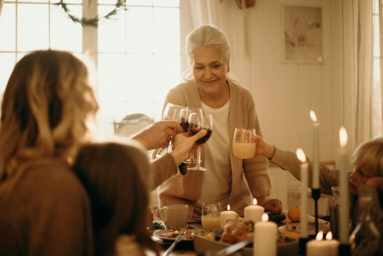 Multigenerational family toasting with wine and juice during candlelit meal.