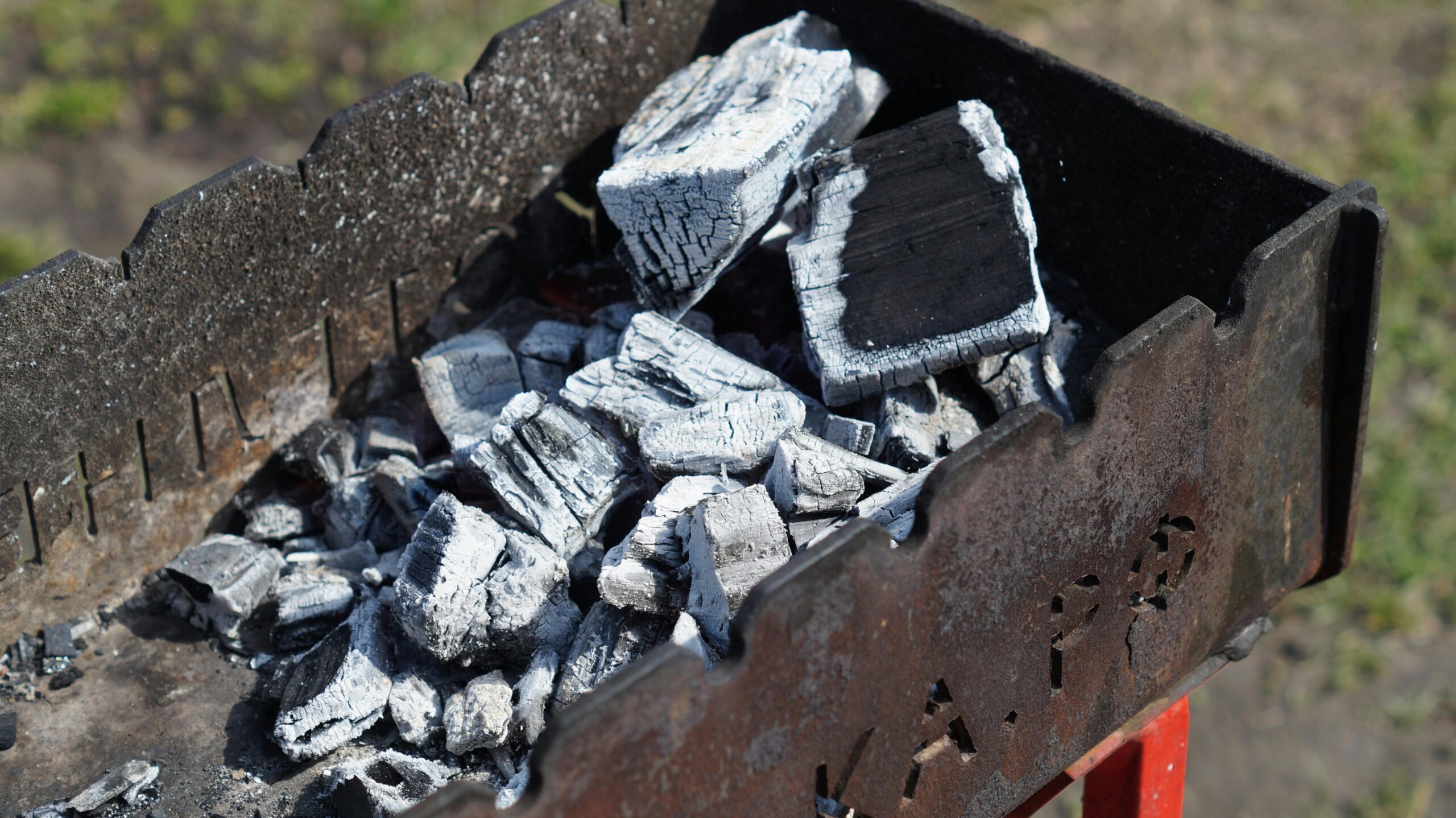 Coals and ashes sit at the bottom of an empty grill.