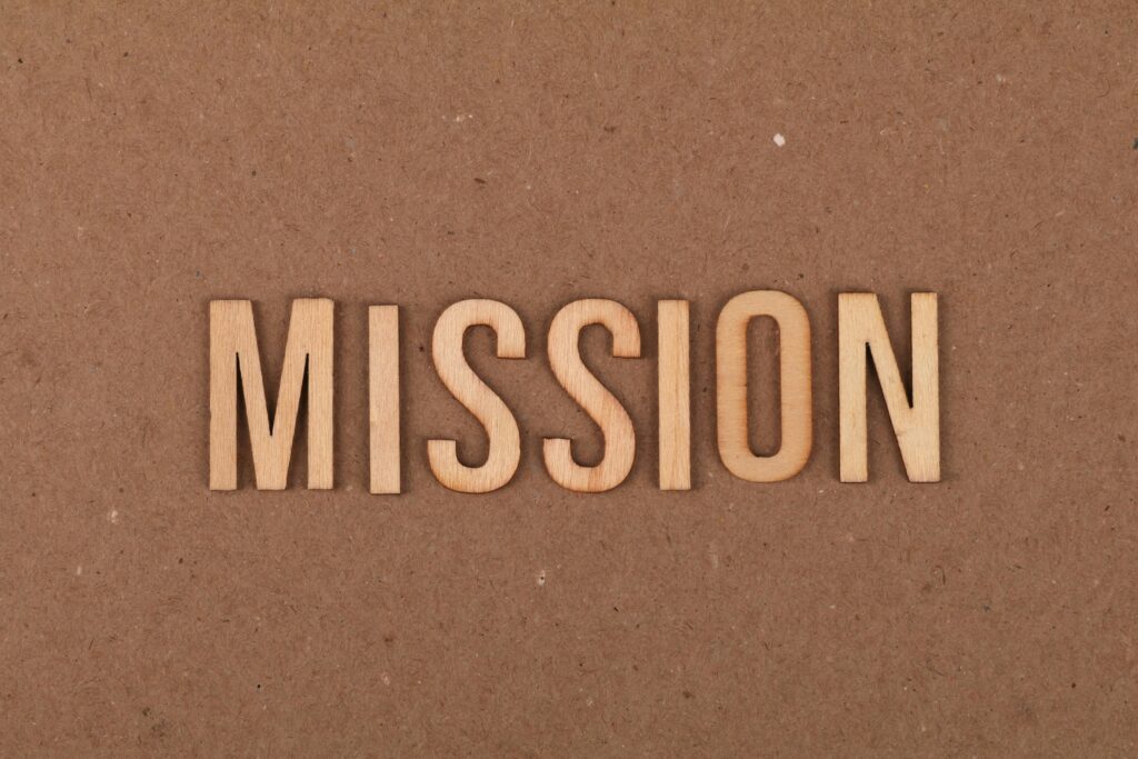 The word "Mission" in wood letters on a brown background.