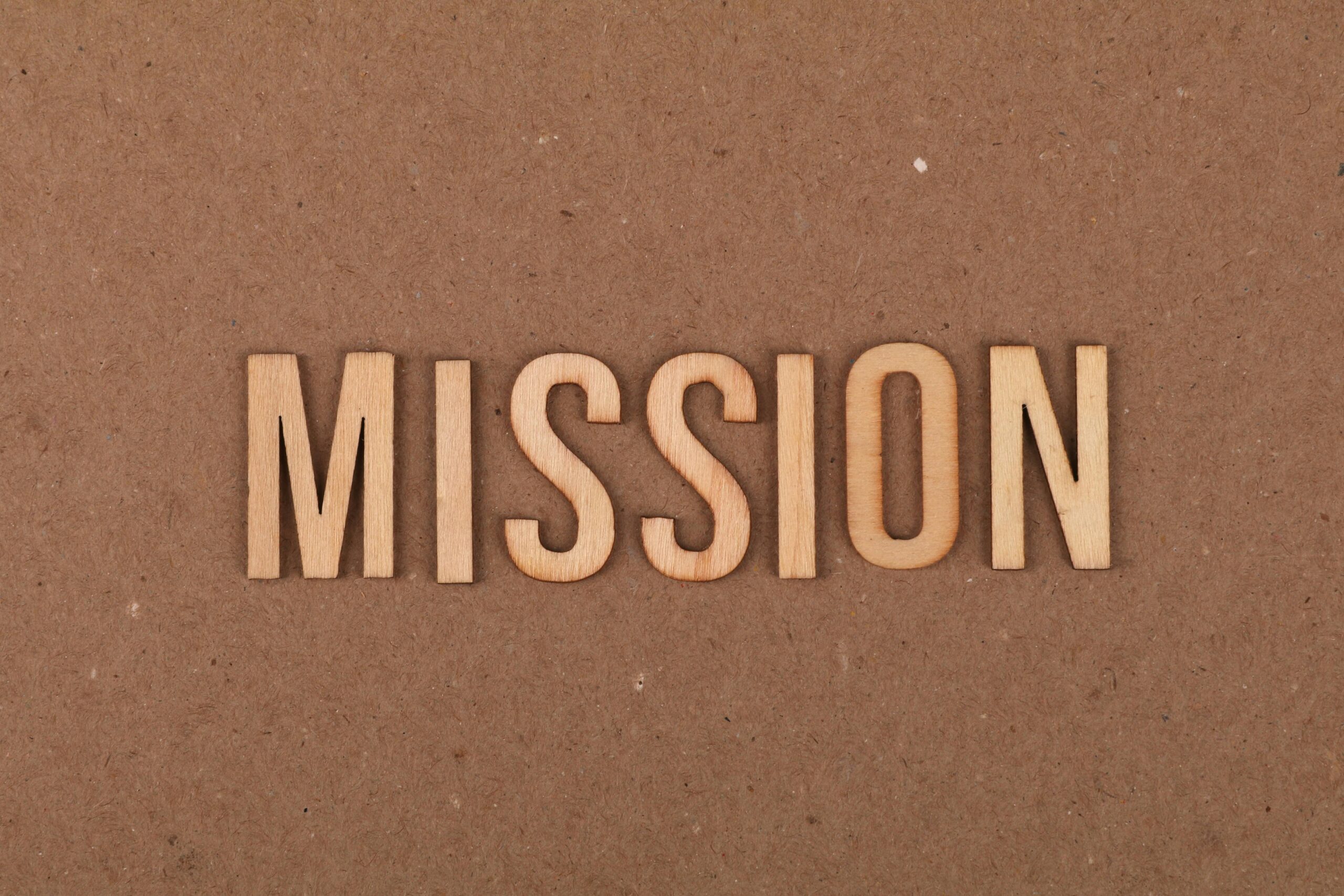 The word "Mission" in wood letters on a brown background.