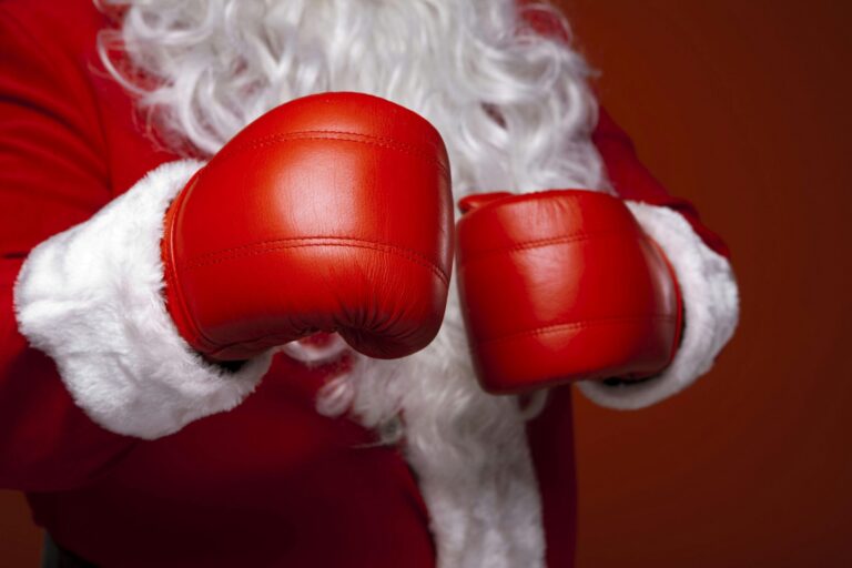 Close-up of Santa Claus wearing red boxing gloves and traditional red suit with white fur trim.