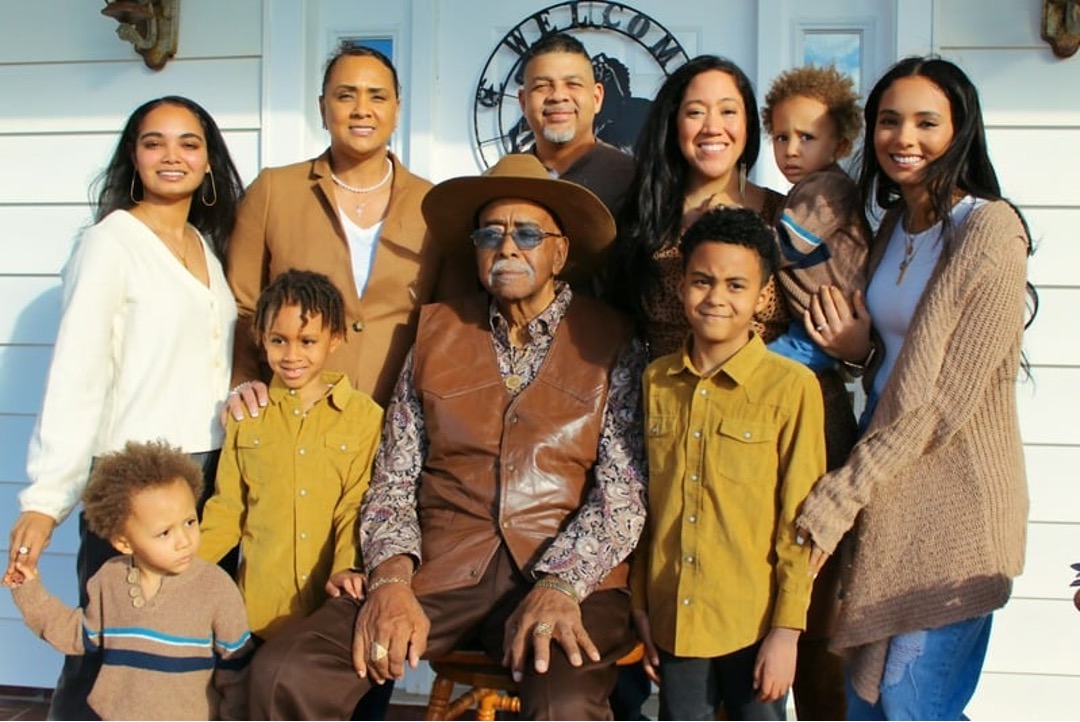 A family poses with multiple generations surrounding the family patriarch.