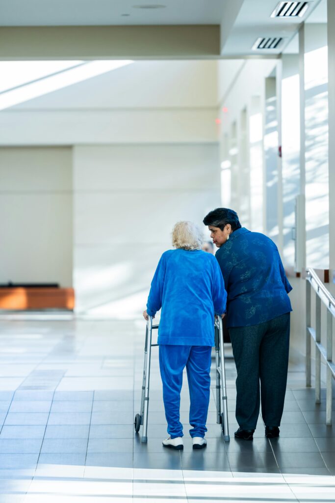 Two elderly women walk together in an independent living facility.
