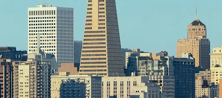 City skyline featuring diverse modern high-rise buildings under a clear blue sky.