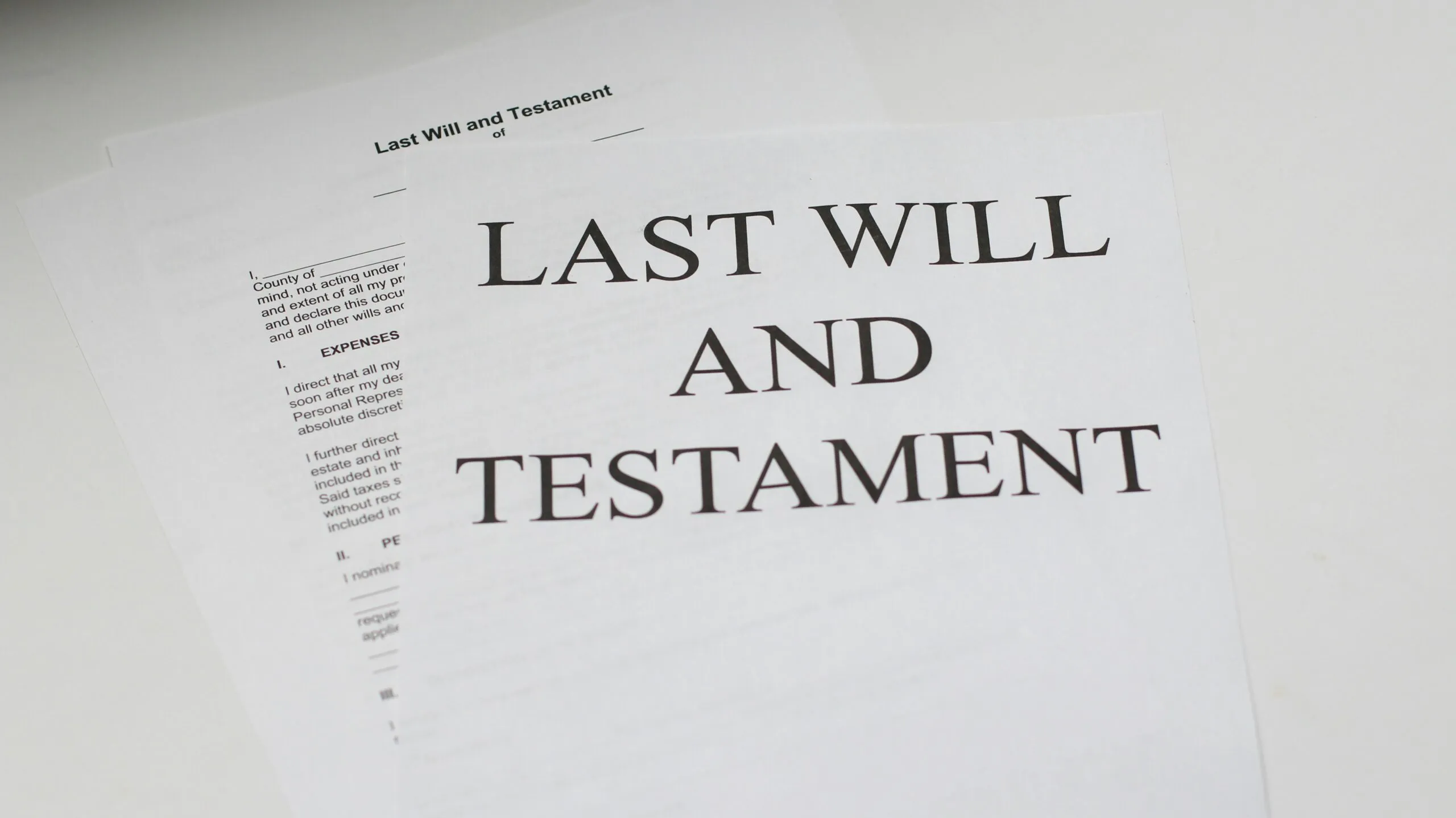 Close-up of printed legal documents titled "Last Will and Testament" on a white surface.