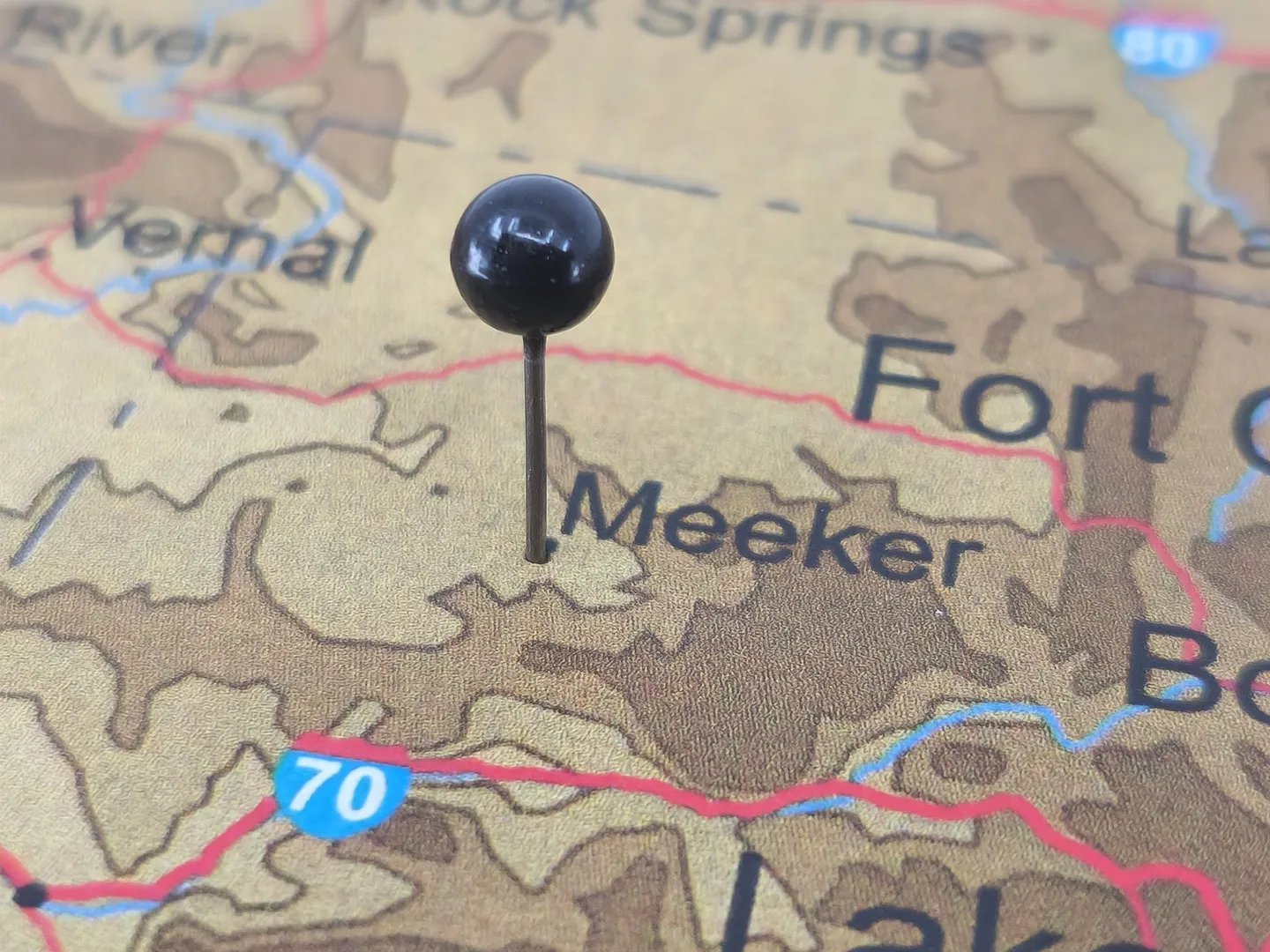 Close-up of a map with a black pin marking Meeker, near Interstate 70.