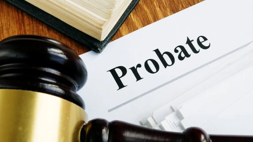 Close-up of a wooden gavel, a legal book, and a document titled "Probate" on a wooden surface.