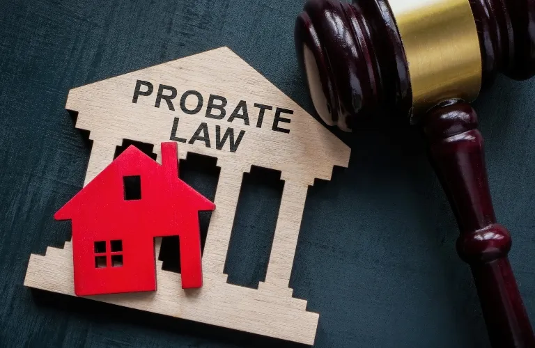 Wooden courthouse model labeled "Probate Law" with a red house figurine and judge's gavel.