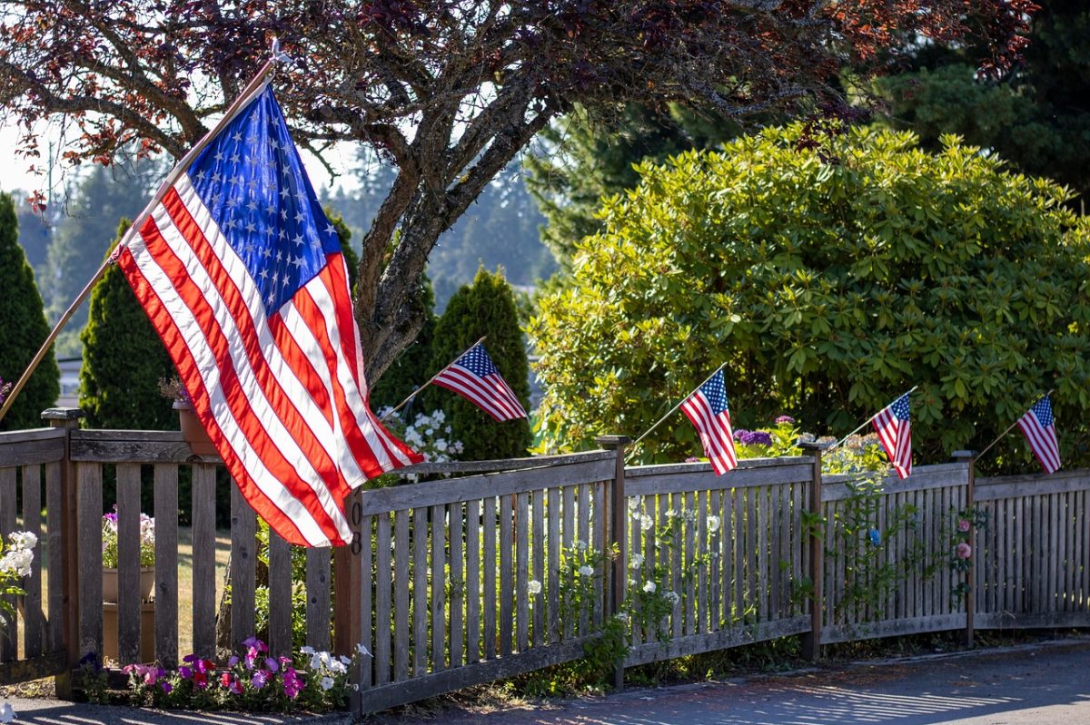 american flags on white picket fence